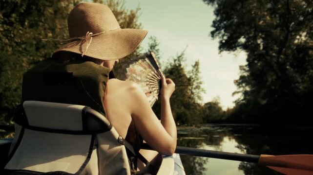 Kayaker Holding Folding Hand Fan Sitting In Boat Floating On River.   Outdoor Recreation. Nature Tourism 