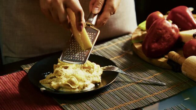 Chef Grating Hard Parmesan Cheese With Grater Over Hot Tortellini Pasta Plate. Italian Culinary 