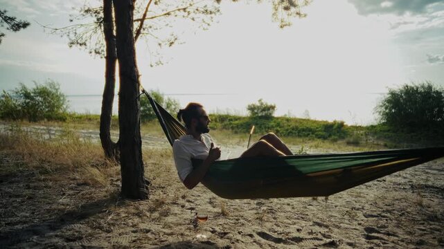 Freelancer Working On Laptop While Lying In Outdoor Hammock Near Lake. Remote Work 
