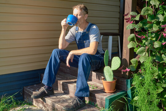 Mature man drinking tea from blue mug on wooden porch in morning