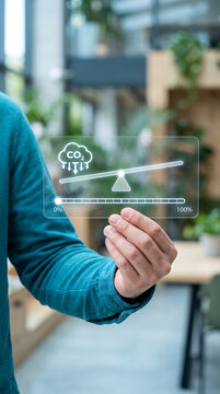 Person interacting with digital interface showing carbon emissions balance scale technology