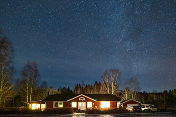 Milky Way starry night sky over traditional red wooden house in winter, Fengersfors, Sweden © Jan