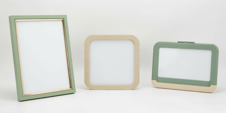 Three empty frames with green and beige borders standing on a plain white background