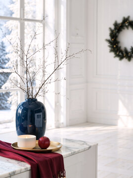 Cozy winter interior with lit candle and red apple on marble table. Minimalist home decor with blue vase and Christmas wreath on white wall