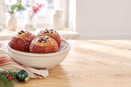 Baked apples stuffed with nuts and raisins in bowl on wooden table. Traditional homemade winter holiday dessert. Copy space for text