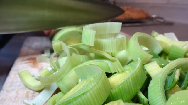 Stockholm, Sweden A cook in a residential kitchen slices fresh green leeks for a soup. 