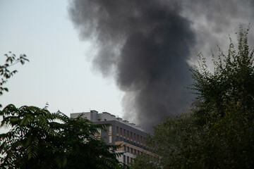 Obraz premium Thick black smoke rises from the top of an apartment building after a drone attack in Ukraine. The concept of fire, missile attack, drone raid