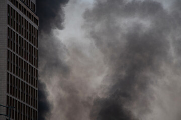 Obraz premium Thick black smoke rises from the top of an apartment building after a drone attack in Ukraine. The concept of fire, missile attack, drone raid