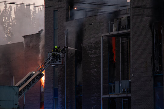 Firefighters put out the burning building of the shopping center. Smoke and fire after a drone attack in Ukraine, rescuers are working at the scene