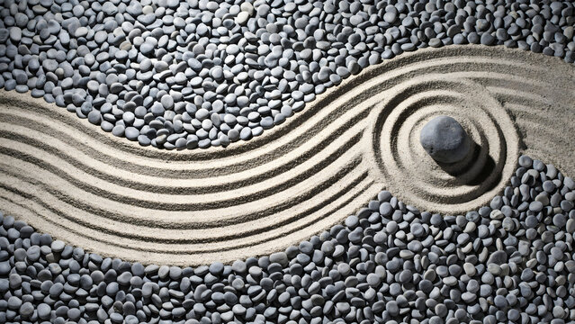 Zen garden arrangement featuring a single dark stone placed in a circular ripple pattern on fine sand surrounded by smooth grey river pebbles