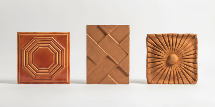 Three square terracotta tiles with intricate embossed geometric and sunburst reliefs
