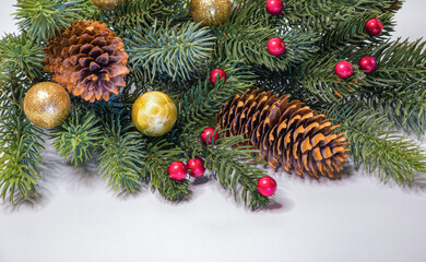 Festive Christmas decoration featuring green fir branches pine cones gold baubles and red berries on a white background perfect for holiday greetings © Tetiana