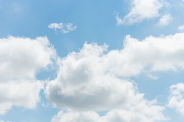 Fototapeta premium Fluffy white clouds against a bright blue sky background with copyspace for text