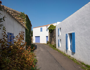 Ruelle pittoresque et maisons blanches traditionnelles aux volets colorés dans le village de Saint-Sauveur, Île d'Yeu, France. © skerdreux