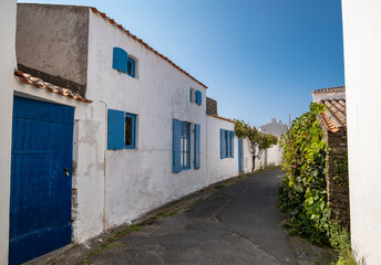 Ruelle pittoresque et maisons blanches traditionnelles aux volets colorés dans le village de Saint-Sauveur, Île d'Yeu, France. © skerdreux