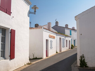Ruelle pittoresque et maisons blanches traditionnelles aux volets colorés dans le village de Saint-Sauveur, Île d'Yeu, France. © skerdreux