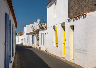 Ruelle pittoresque et maisons blanches traditionnelles aux volets colorés dans le village de Saint-Sauveur, Île d'Yeu, France. © skerdreux