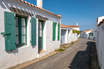 Ruelle pittoresque et maisons blanches traditionnelles aux volets colorés dans le village de Saint-Sauveur, Île d'Yeu, France. © skerdreux
