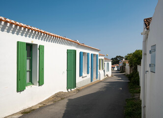Ruelle pittoresque et maisons blanches traditionnelles aux volets colorés dans le village de Saint-Sauveur, Île d'Yeu, France. © skerdreux
