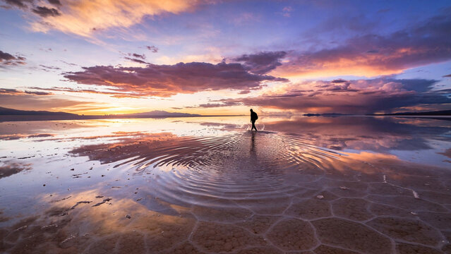 Lone Silhouette Walking Flooded Salt Flat at Vivid Sunset