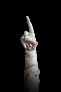 Mummy's hand wrapped in a bandage creepily pointing on isolated background. The hand of the mummy monster for Halloween horror concept