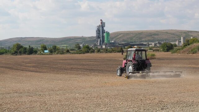 Farmer driving tractor tilling the dusty dry soil