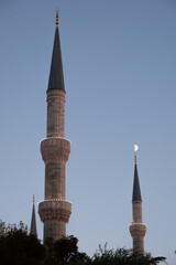 Mosque minarets with crescent moon against blue evening sky in Istanbul © Aleksandr