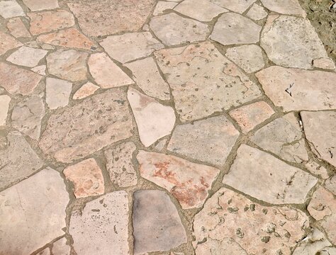 ​Stone pavement pattern texture background made of irregular natural stone tiles on sidewalk