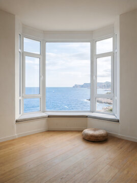 Bay window view of the blue sea and rocky coastline with coastal living room seaside home interior design