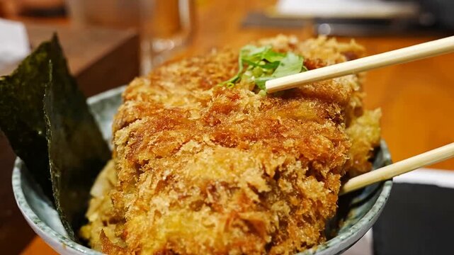 Thick cut of fried pork tonkatsu with crispy golden breadcrumbs placed in a bowl with japanese side dishes for a traditional meal