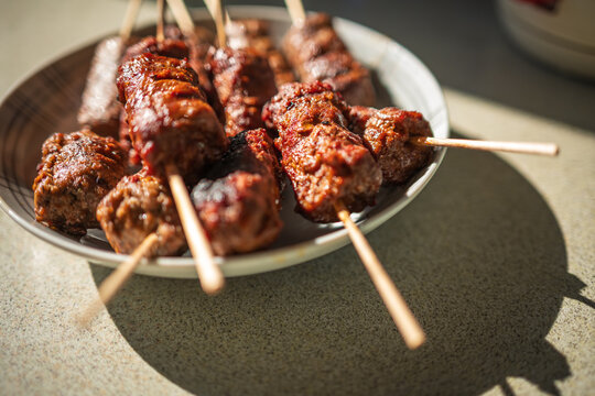 Grilled Meat Skewers and Spicy Satay on Plate Close-Up, Barbecue Street Food Platter