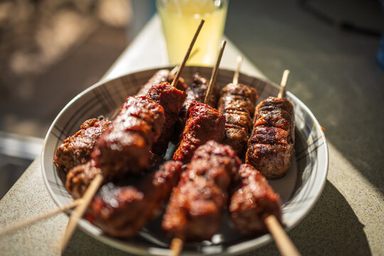 Grilled Meat Skewers and Spicy Satay on Plate Close-Up, Barbecue Street Food Platter