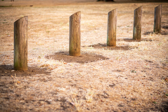 Wooden Bollards and Posts Lining Dry Grass Parkland on a Hot Summer Day in England UK