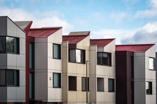 Modern Residential Townhouses in Suburban Street With Colorful Facades, Cars and Urban Landscaping in England UK