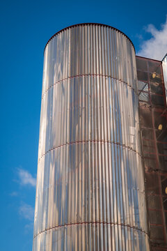 Modern Metal Cylinder Facade On Contemporary Building Against Clear Blue Sky With Single Cloud