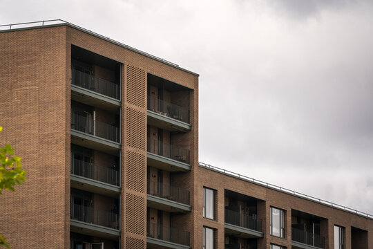 Modern Brick Apartment Building With Balconies Under Overcast Urban Sky in England UK