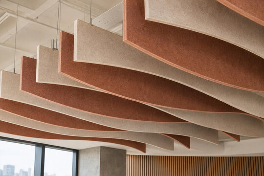 Curved felt acoustic ceiling baffles in terracotta and cream