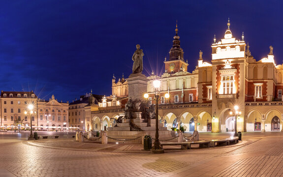 Illuminated Cloth Hall and Adam Mickiewicz Monument on Main Market Square in Krakow, Poland, during blue hour.