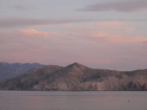 pink sunset over a mountain by the sea in Baska, Croatia