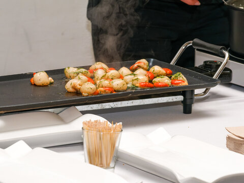 Noix de Saint-Jacques po&ecirc;l&eacute;es aux herbes servies chaudes sur une plaque lors d&rsquo;un buffet traiteur