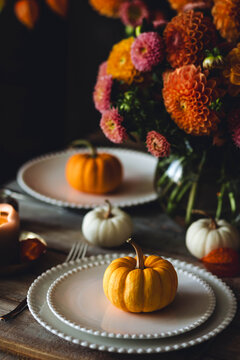 Fall table decoration with pumpkin composition. Family cozy thanksgiving dinner arrangement indoors, elegant wedding decor. Countryside style, candle light, autumn mood. Dark background