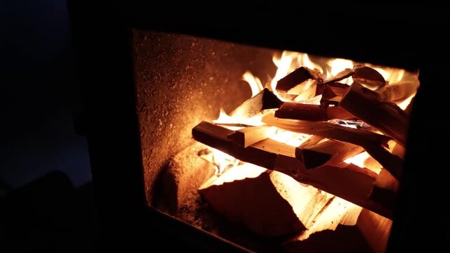 Cozy fireplace glow with stacked logs in dark brick interior, warm amber light and rustic hearth mood for quiet evening home comfort