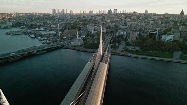 Turkey, Istanbul 06 10 2025: 4K drone video moving forward along Golden Horn Metro Bridge over Halic Station at early sunrise with Sokullu Mosque and city skyline in background.