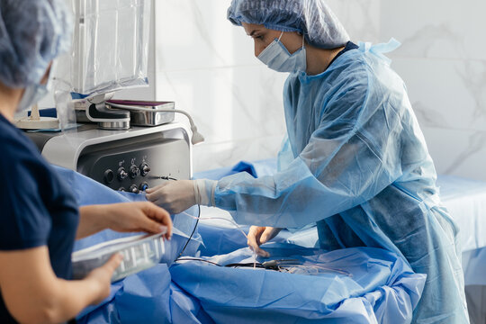 Nurse in sterile gown and face mask setting up phacoemulsification system for cataract surgery in eye clinic