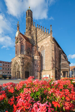 Frauenkirche church in Nuremberg, Germany, standing beside Hauptmarkt with bright red flowers, Gothic details and old town architecture