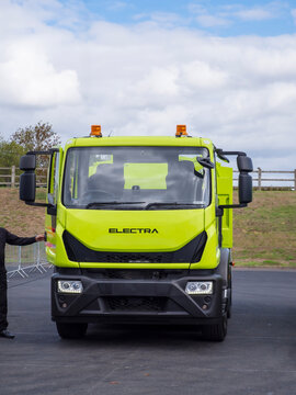 Birmingham, UK - September 17th September: Front view lime green heavy duty electric truck cab with amber roof beacons, large side mirrors, and bright headlight details parked outdoors on asphalt