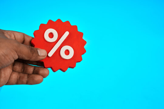 A hand holding a percentage symbol represents interest rates discounts financial costs and changing market conditions.
