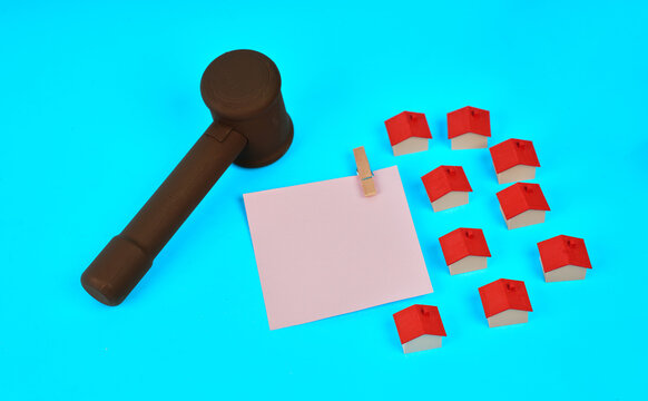 A judge gavel beside miniature houses and a blank document represents real estate law property contracts and legal housing agreements.
