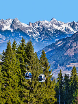 Gondola cabins over pine forest and peaks at Zell am See