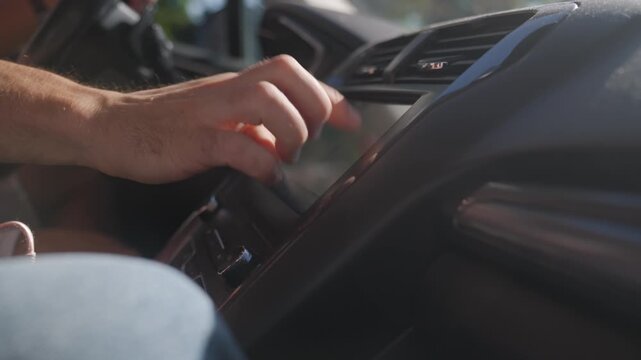 Person taps touchscreen display on car dashboard with finger. Using digital infotainment controls and vehicle technology inside car